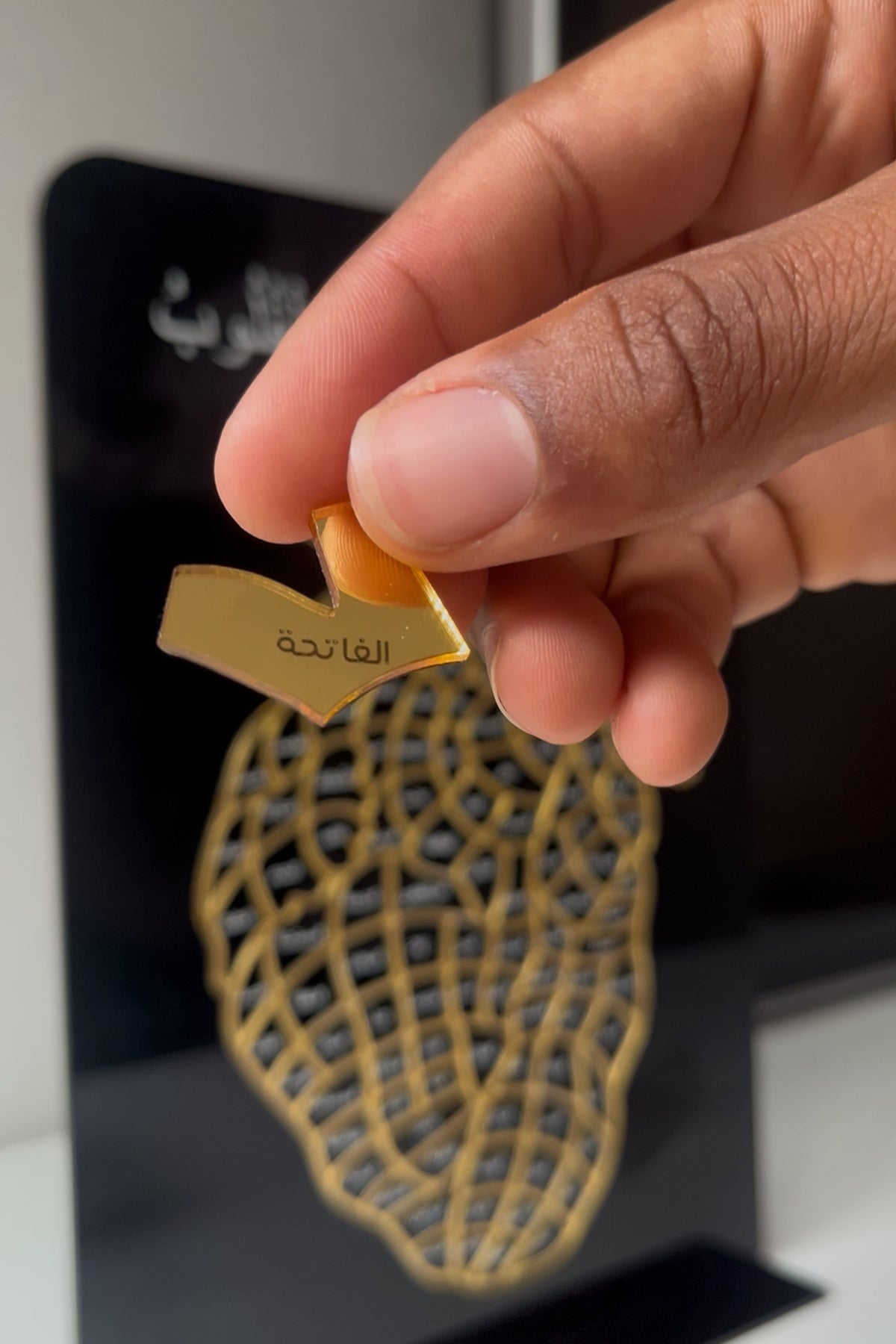Main plaçant une pièce dorée gravée d'une sourate sur le cœur
